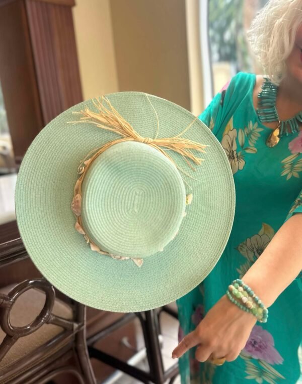 Sombrero de paja con ala ancha, adornado con caracoles marinos naturales. Un toque original y veraniego para tus looks.
